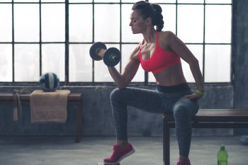 a woman holding a free weight in a gym