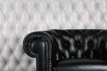 tufted black leather couch on grey leather background
