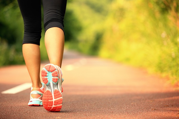 young fitness woman legs walking on forest trail