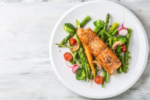 salmon on fresh veggies on a white dish