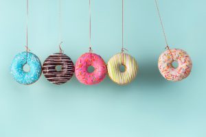 donuts hanging from strings on blue background sugar causes candida overgrowth